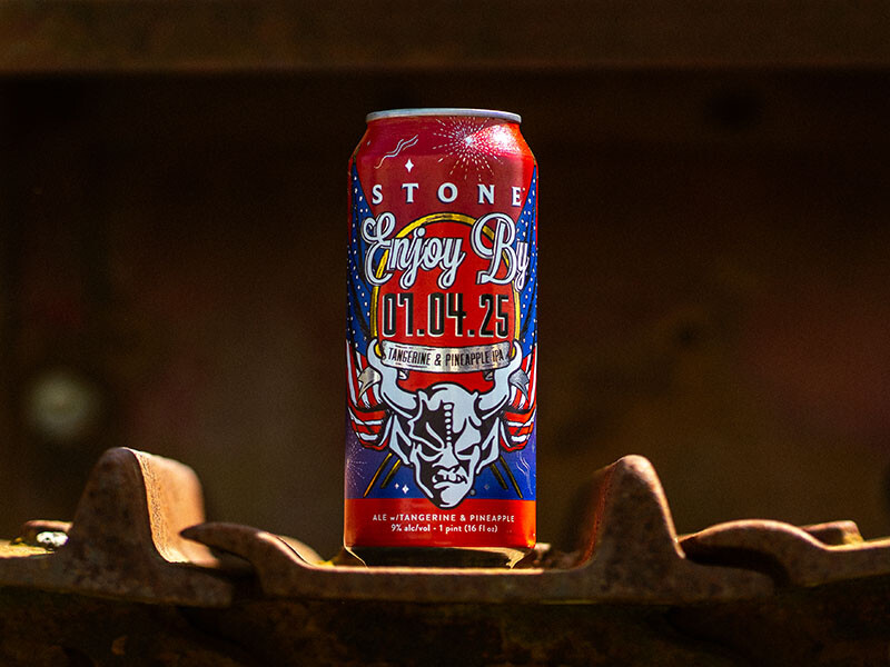 can of Stone Enjoy By 07.04.25 Tangerine & Pineapple IPA beer on a tractor wheel
