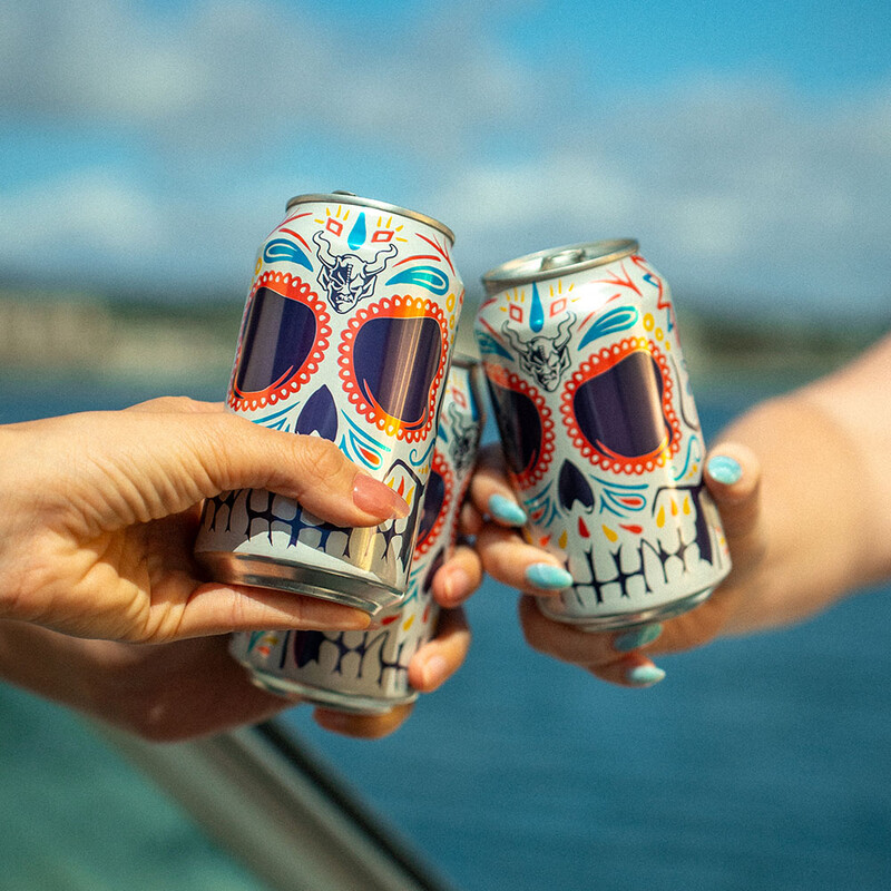 three people cheersing Stone Buenaveza Lager beer cans