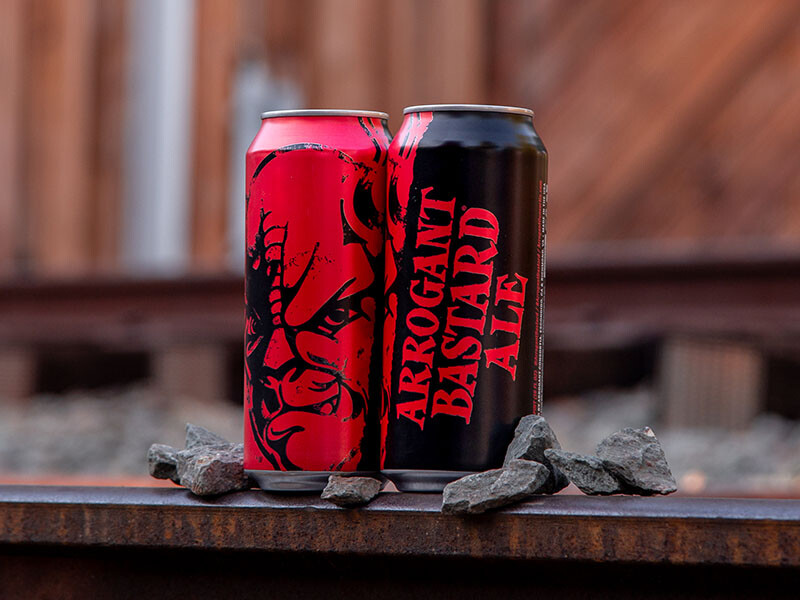 Arrogant Bastard Ale cans on railroad tracks with rocks