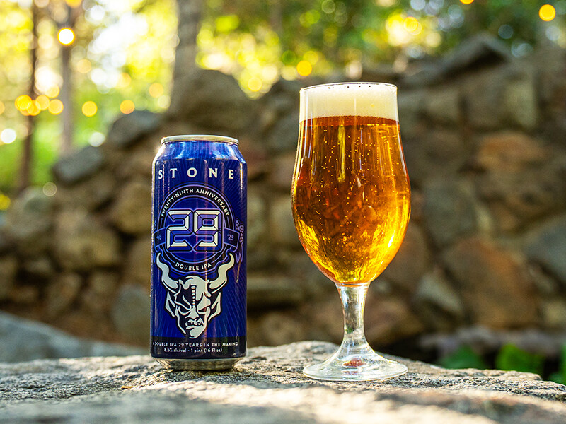 stone 29th anniversary double ipa can next to beer in glass